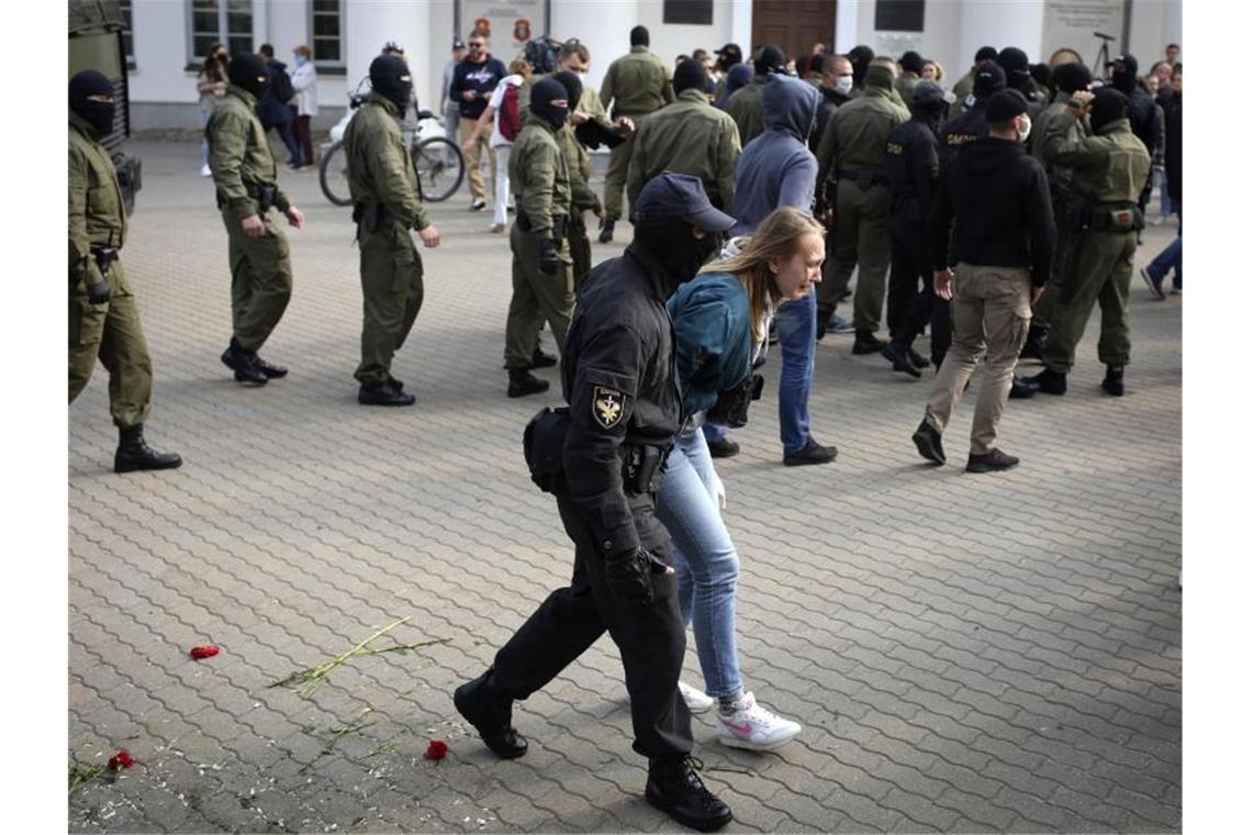 Ein Polizist führt eine Frau ab. Foto: -/Tut.by via AP/dpa