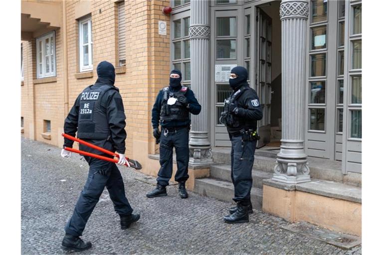 Ein Polizist geht bei einer Razzia mit einem Bolzenschneider in ein Haus in der Hauptstadt. Mit einer Großrazzia ist die Polizei am Donnerstag gegen Clankriminalität in Berlin und Umgebung vorgegangen. Foto: Christophe Gateau/dpa