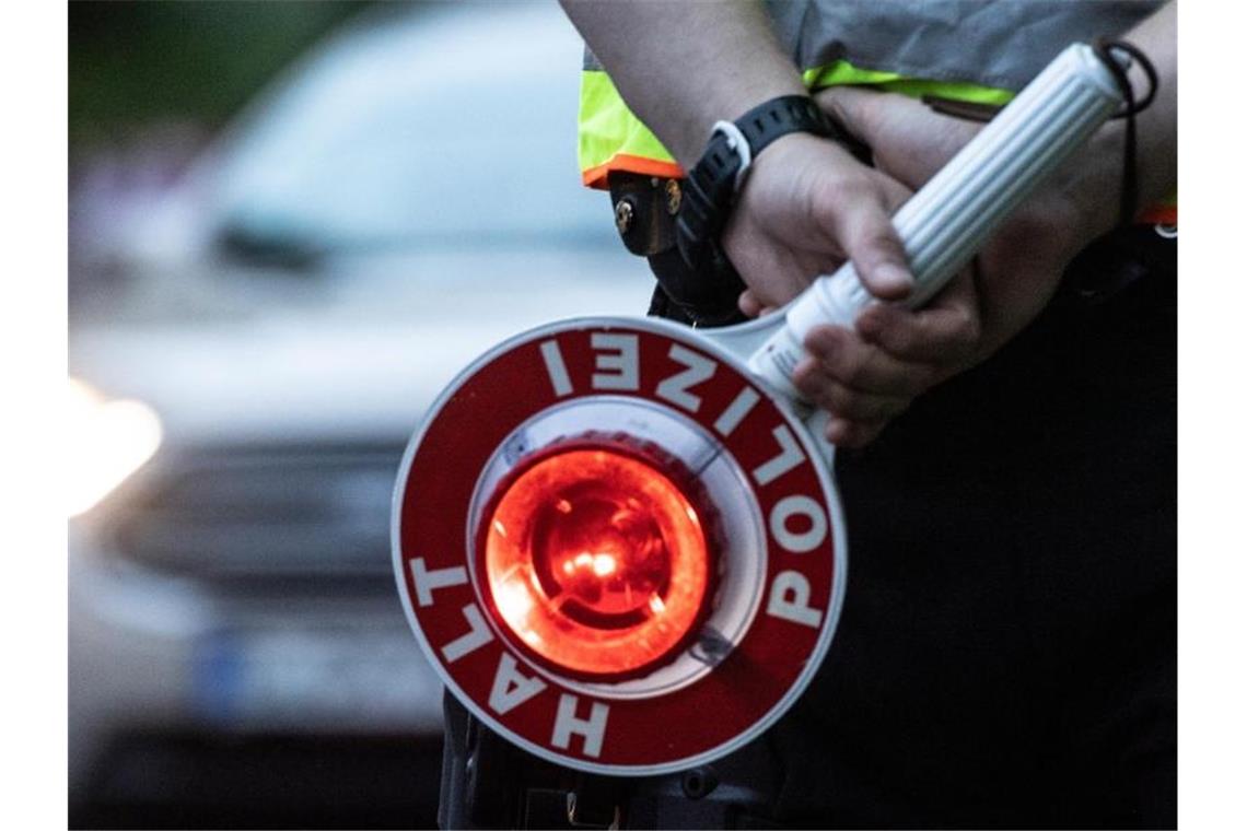 Betrunkener bleibt mit Auto im Graben stecken: Drei Promille Ein Polizist hält an einer Kontrollstelle eine Winkerkelle in der Hand. Foto: Paul Zinken/dpa/ZB/Symbolbild
