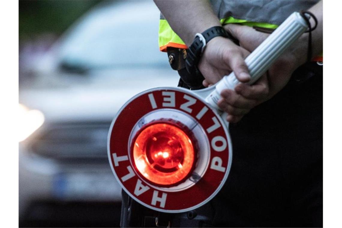 Ein Polizist hält an einer Kontrollstelle eine Winkerkelle in der Hand. Foto: Paul Zinken/dpa/ZB/Symbolbild