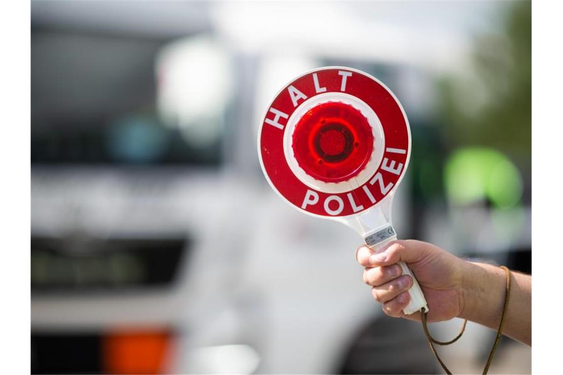 Zoll stoppt Fahrer mit Hunderttausenden Potenzpillen im Auto Ein Polizist hält bei einer Verkehrskontrolle eine Polizeikelle in der Hand. Foto: Jonas Güttler/dpa/Symbolbild