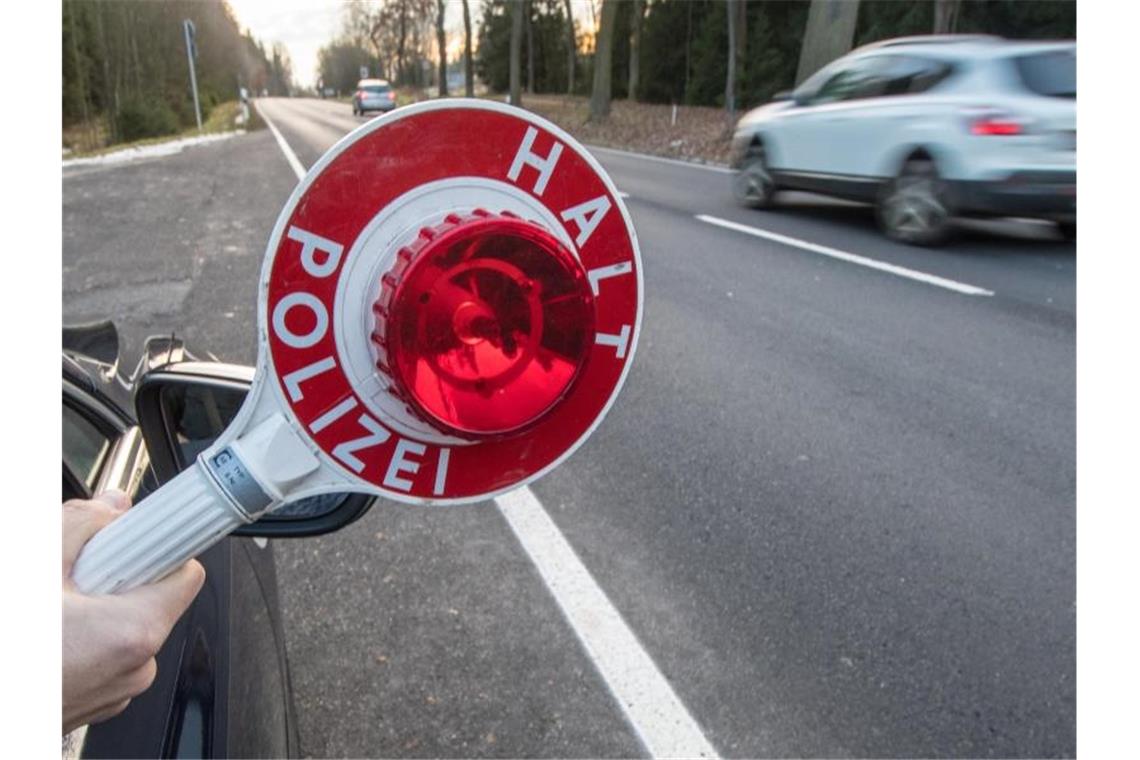 Hochzeitskorso gefährdet Autofahrer auf der Autobahn Ein Polizist hält eine Polizeikelle. Foto: Armin Weigel/Archiv