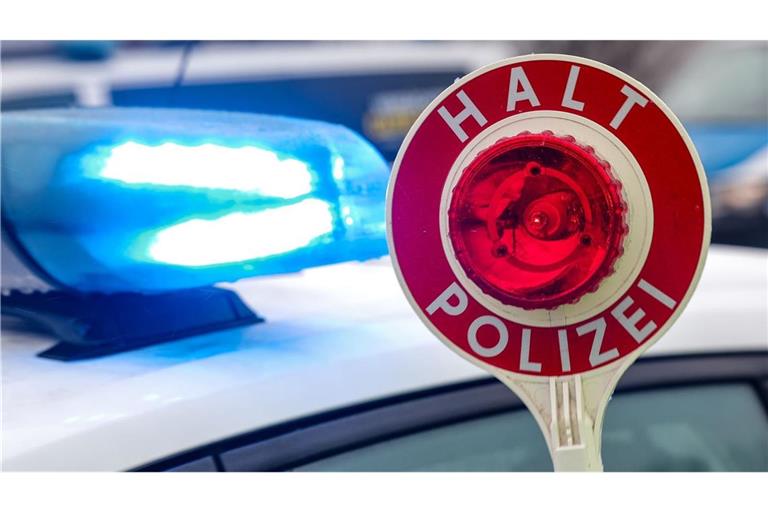 Ein Polizist hält eine Polizeikelle für eine Kontrolle hoch. (zu dpa: «Kein Platz im Auto? Junger Mann fährt auf dem Dach mit»)