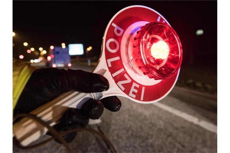 Ein Polizist hält während einer Verkehrskontrolle mit einer Haltekelle Fahrzeuge an. Foto: Patrick Seeger/Archivbild