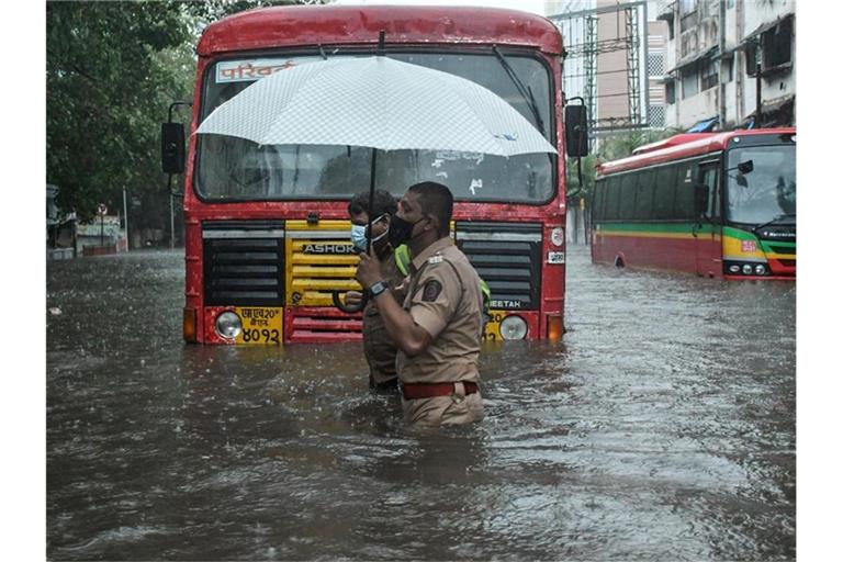 Ein Polizist hilft in Mumbai einem Fahrer eines öffentlichen Verkehrsmittels, eine überschwemmte Straße zu überqueren. Foto: Ashish Vaishnav/SOPA Images via ZUMA Wire/dpa