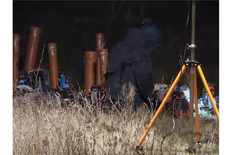 Ein Polizist in Schutzausrüstung untersucht den Unfallort in Rietz-Neuendorf. Foto: Christian Sappeck/BLP/dpa