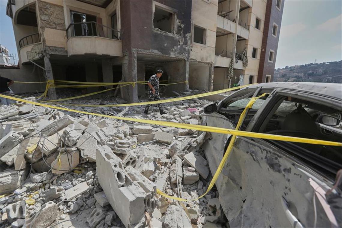 Ein Polizist inspiziert die Schäden an einem Gebäude.