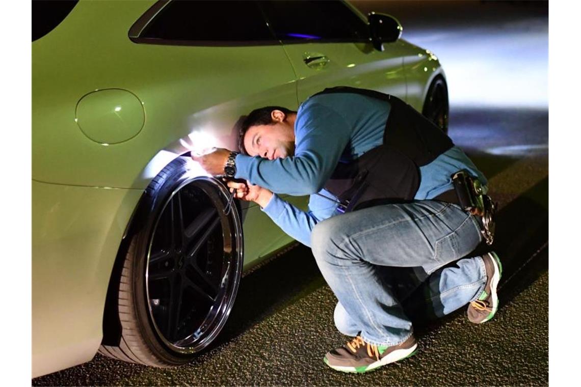 Verkehrsgerichtstag: Flensburg-Punkte für aggressives Posen Ein Polizist kontrolliert in Mannheim das Auto eines mutmaßlichen Autoposers. F. Foto: Uwe Anspach/dpa