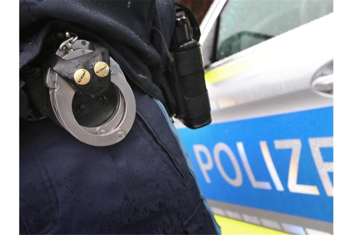 Mann in Rottenburger City bedroht Menschen mit Messer Ein Polizist mit Handschellen und einer Pistole am Gürtel steht vor einem Streifenwagen. Foto: Karl-Josef Hildenbrand/dpa