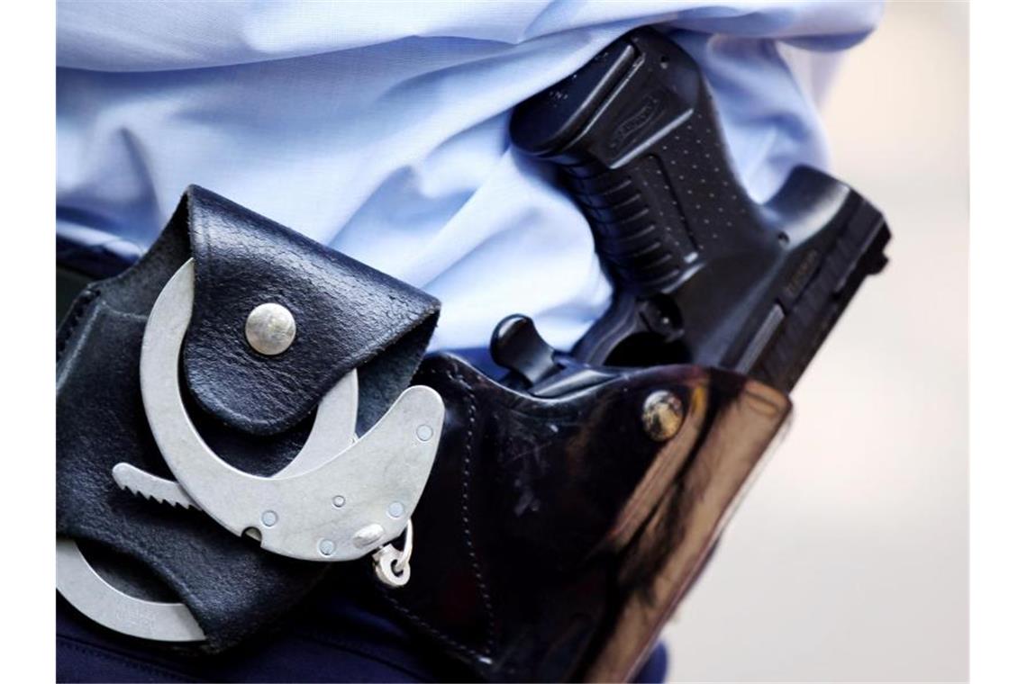 Ein Polizist mit Handschellen und Pistole am Gürtel. Foto: Oliver Berg/dpa