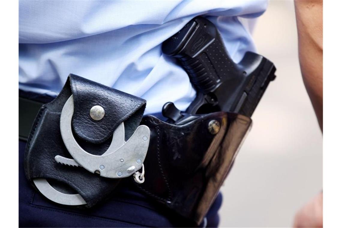 Ein Polizist mit Handschellen und Pistole am Gürtel. Foto: Oliver Berg/dpa/Symbolbild/Archivbild