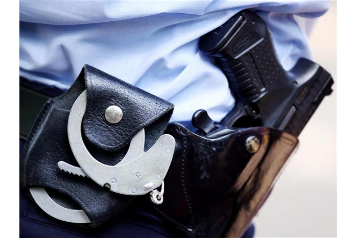 Ein Polizist mit Handschellen und Pistole am Gürtel. Foto: Oliver Berg/dpa