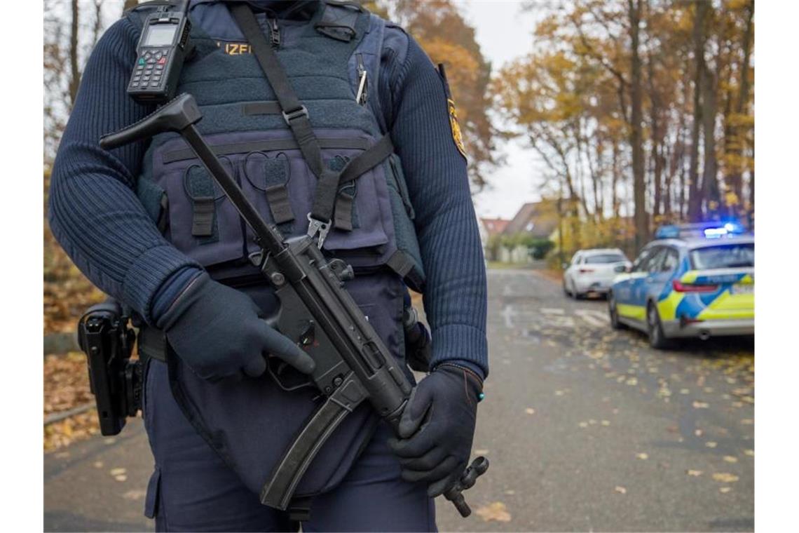 Zwei Menschen auf offener Straße in Nürnberg erschossen Ein Polizist mit schwerem Geshütz bewacht die Zufahrt zu einem Wohnviertel, indem zwei Menschen erschossen worden sind. Foto: Daniel Karmann/dpa