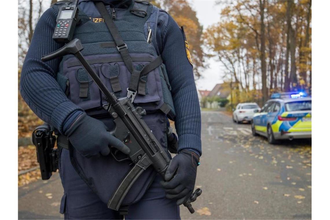 Ein Polizist mit schwerem Geshütz bewacht die Zufahrt zu einem Wohnviertel, indem zwei Menschen erschossen worden sind. Foto: Daniel Karmann/dpa