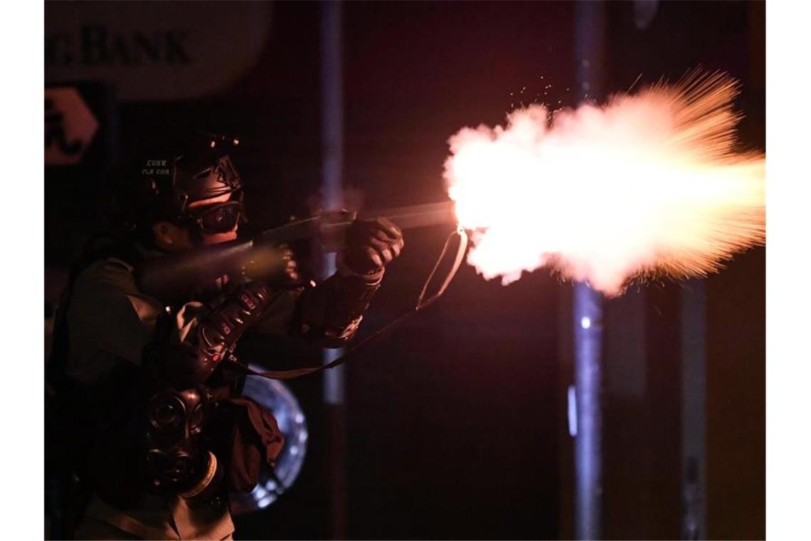 Ein Polizist schießt Tränengas auf Demonstranten. Foto: -/kyodo/dpa