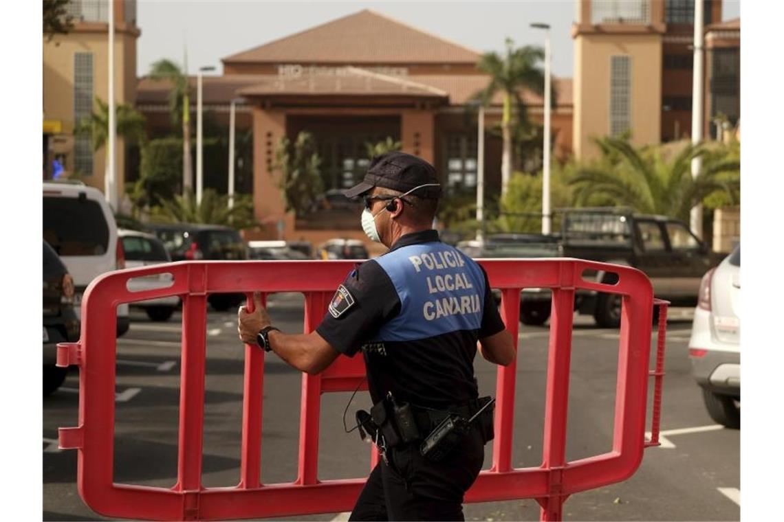 Ein Polizist setzt eine Sperre, die den Zugang zum Hotel H10 Costa Adeje Palace auf Teneriffa blockiert. Foto: AP/dpa