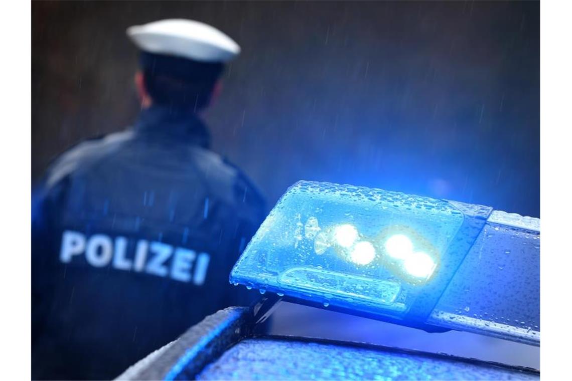 Staatsschutz ermittelt nach möglichen Schüssen in Heilbronn Ein Polizist steht im Regen vor einem Streifenwagen dessen Blaulicht aktiviert ist. Foto: Karl-Josef Hildenbrand/dpa/Archivbild