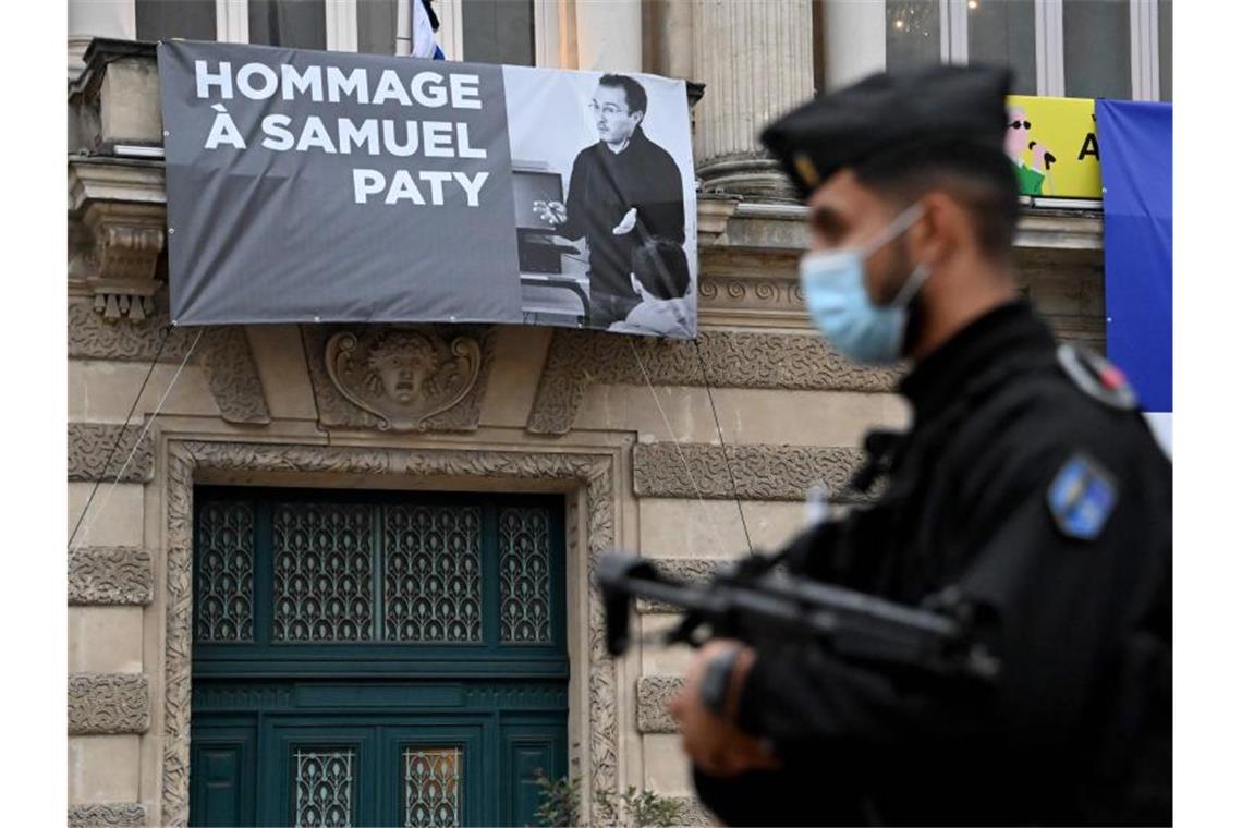 Ein Polizist steht neben der Opera Comedie in Montpellier, an deren Fassade eine Hommage an den enthaupteten Lehrer Samuel Paty angebracht ist. Foto: Pascal Guyot/AFP/dpa