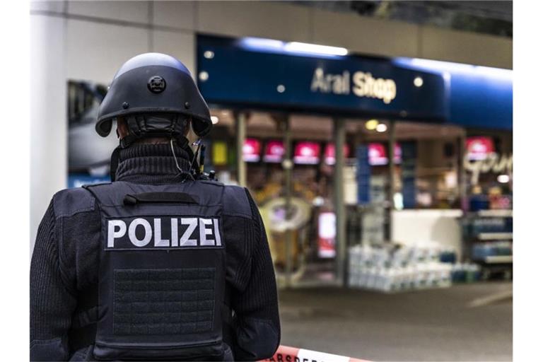 Ein Polizist steht vor der Tankstelle, an der ein Angestellter von einem Mann erschossen worden ist. Foto: Christian Schulz/Foto Hosser/dpa