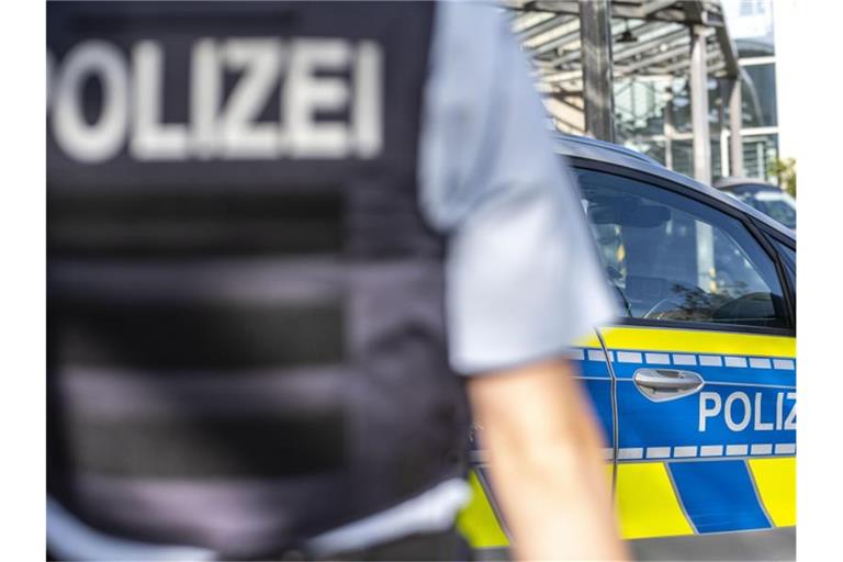 Ein Polizist steht vor einem Streifenwagen. Foto: David Inderlied/dpa/Symbolbild