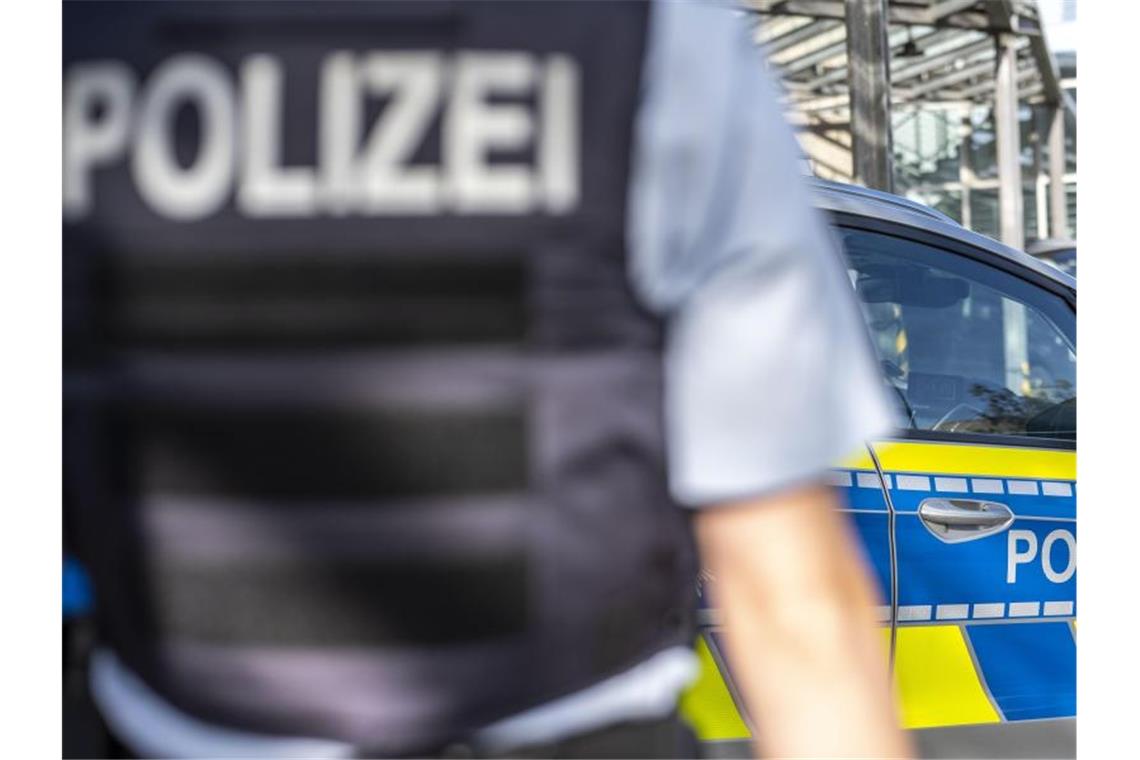 Ein Polizist steht vor einem Streifenwagen. Foto: David Inderlied/dpa/Illustration