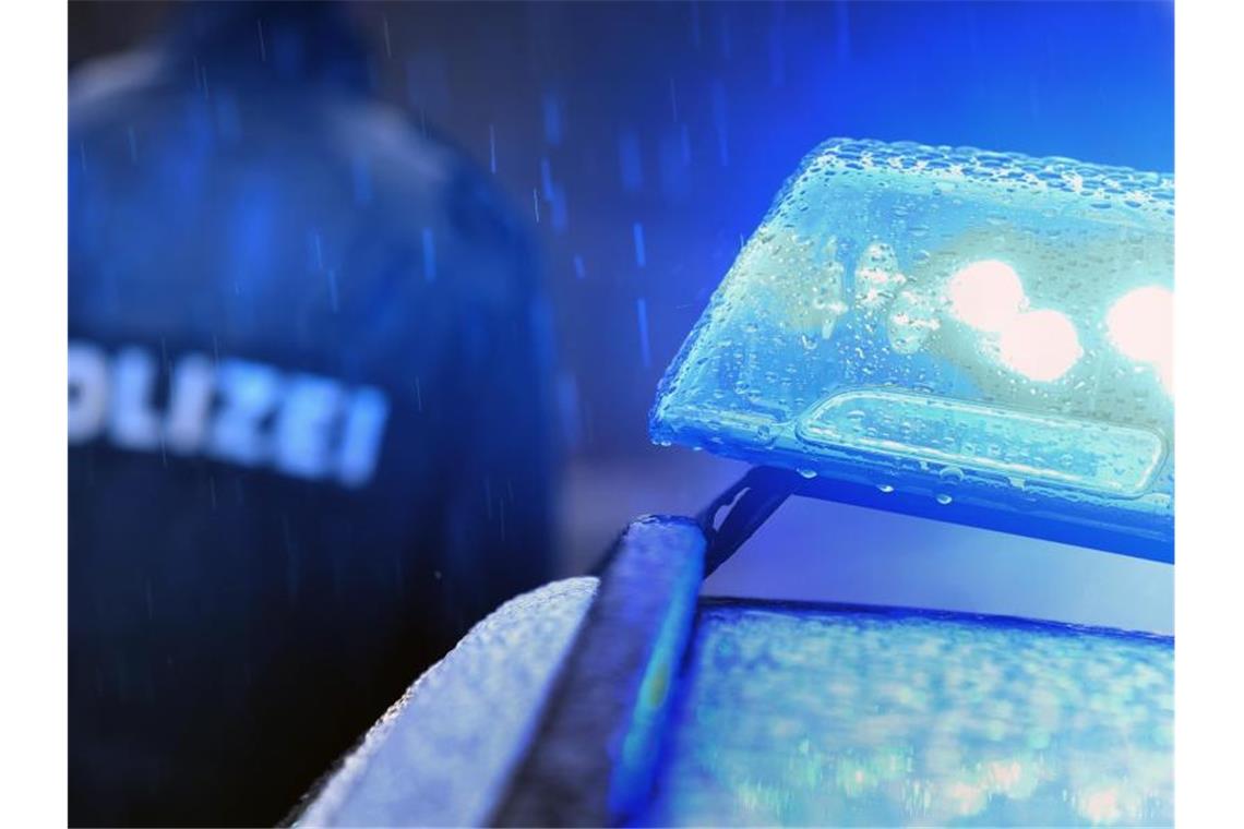Ein Polizist steht vor einem Streifenwagen mit Blaulicht. Foto: Karl-Josef Hildenbrand/dpa/Symbolbild