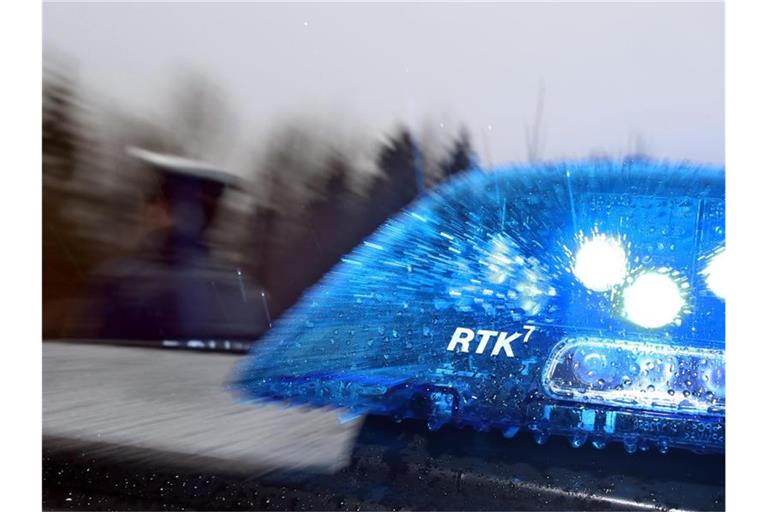 Ein Polizist steht vor einem Streifenwagen mit Blaulicht. Foto: Karl-Josef Hildenbrand/dpa/Archivbild