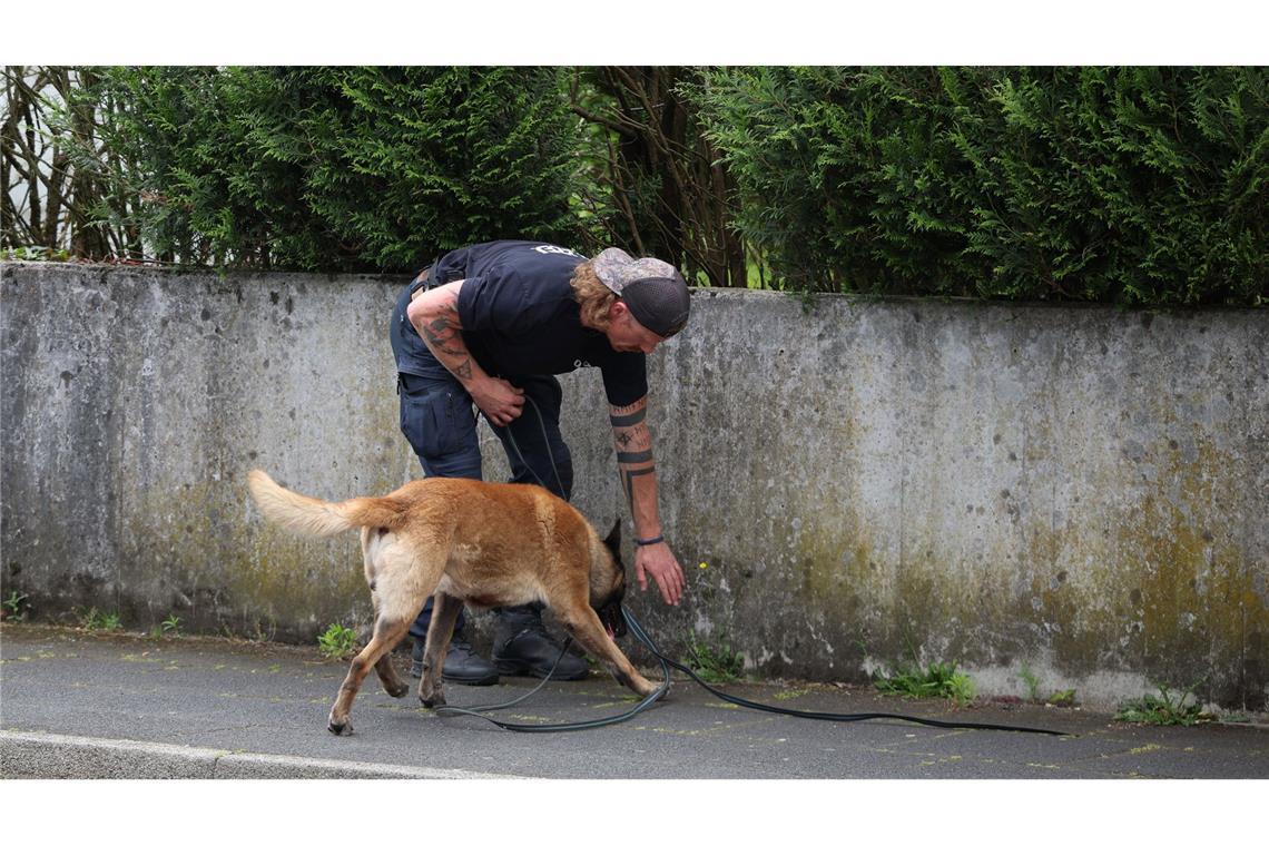 Ein Polizist sucht mit einem Spürhund nach Hinweisen.