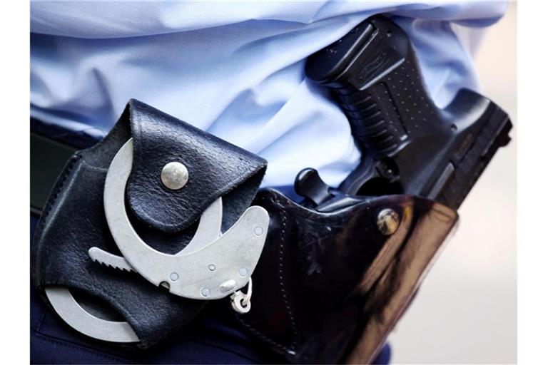 Ein Polizist trägt Handschellen und Pistole am Gürtel. Foto: picture alliance/dpa/Symbolbild