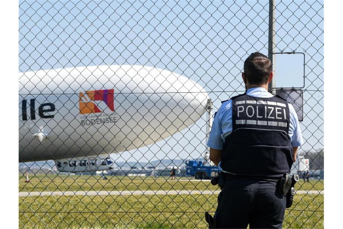 Ein Polizist verfolgt vom Zaun aus den Start des Zeppelin NT (Neue Technik). Foto: Felix Kästle/dpa