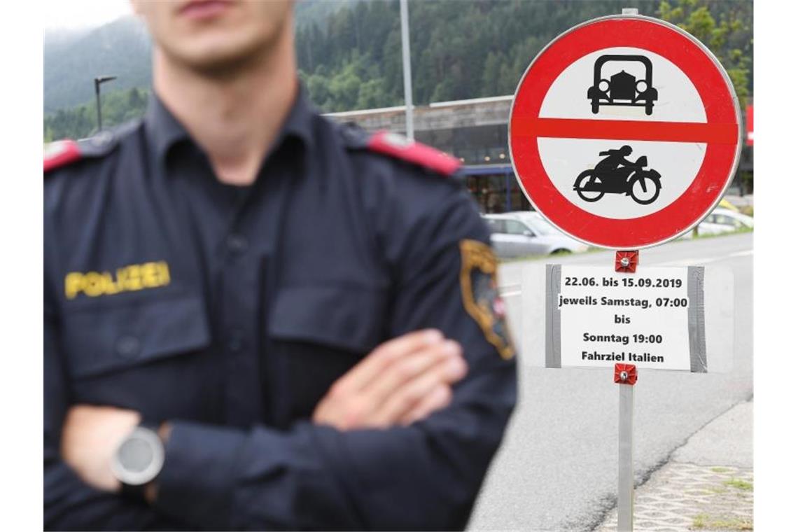 Polizei setzt Fahrverbote in Tirol durch Ein Polizist vor einem Schild, das auf die Sperrung für den Verkehr mit Fahrziel Italien hinweißt. Foto: Angelika Warmuth