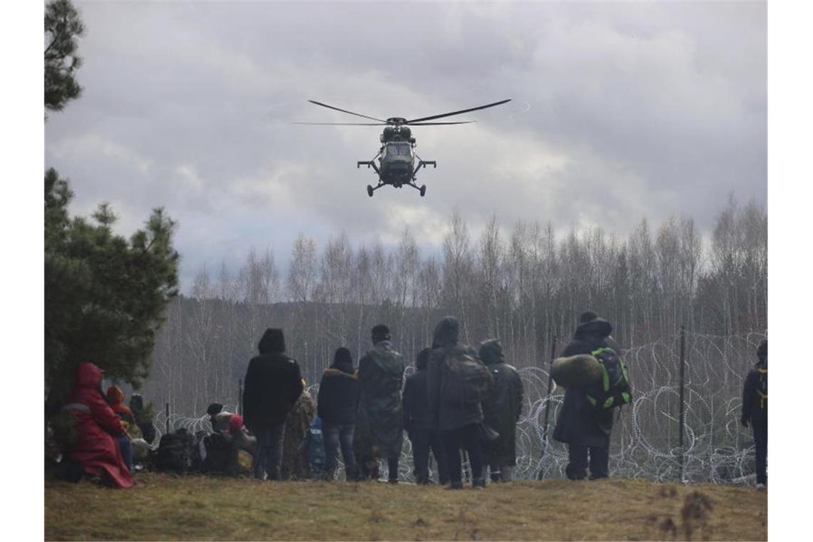 Ein polnischer Militärhubschrauber fliegt über eine Gruppe Migranten, die sich an der weißrussisch-polnischen Grenze versammelt haben. Foto: Leonid Shcheglov/BelTA/AP/dpa