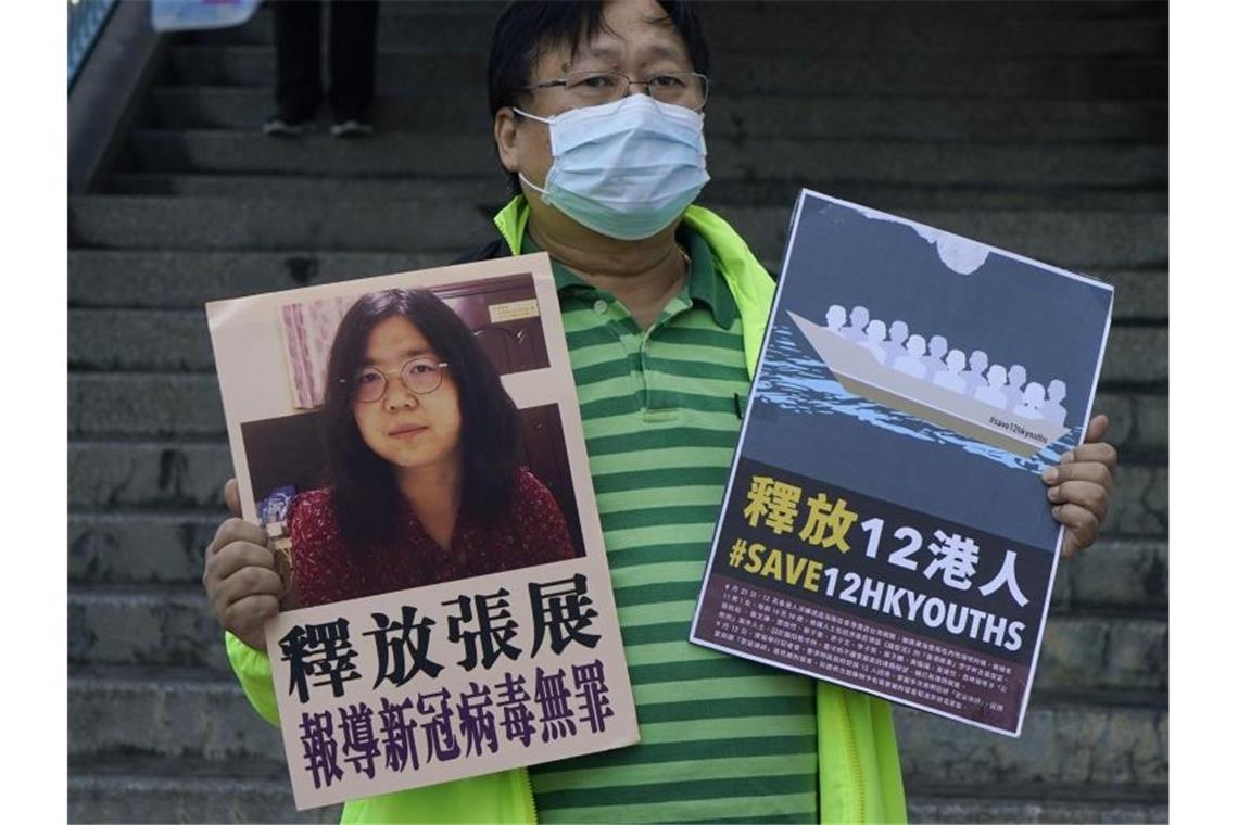 Ein pro-demokratischer Aktivist zeigt zwei Plakate vor dem Verbindungsbüro der chinesischen Zentralregierung. Auf einem Plakat ist ein Foto der chinesischen Journalistin Zhang Zhan zu sehen. Foto: Kin Cheung/AP/dpa