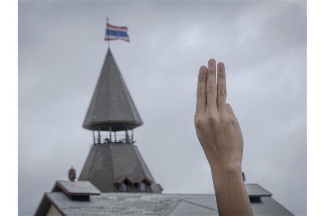 Ein pro-demokratischer Demonstrant erhebt während einer Demonstration im Sanam-Luang-Park drei Finger als Symbol des Widerstands. Foto: Wason Wanichakorn/AP/dpa