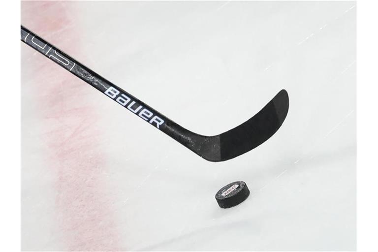 Ein Puck liegt vor einem Schläger im Spiel auf dem Eis. Foto: Daniel Karmann/dpa/Symbolbild
