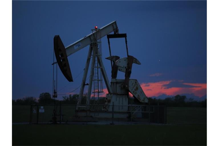 Ein Pumpe arbeitet bei Sonnenuntergang in einem Ölfeld. Der Höhenflug der Ölpreise hält an. Am Montagmorgen markierten die beiden wichtigsten Erdölsorten abermals mehrjährige Höchststände. Foto: Sue Ogrocki/AP/dpa
