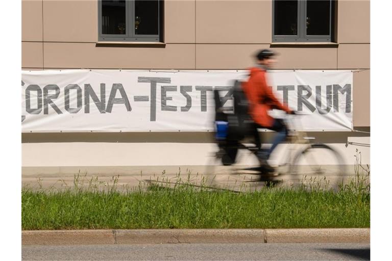 Ein Radfahrer fährt an einem Banner mit der Aufschrift "Corona-Testzentrum" vorbei. Foto: Robert Michael/dpa-Zentralbild/dpa/Symbolbild