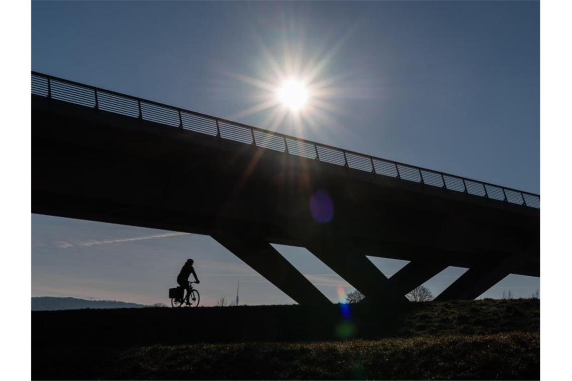 Ein Radfahrer fährt bei Sonnenschein unter einer Brücke entlang. Foto: Robert Michael/dpa-Zentralbild/ZB/Symbolbild