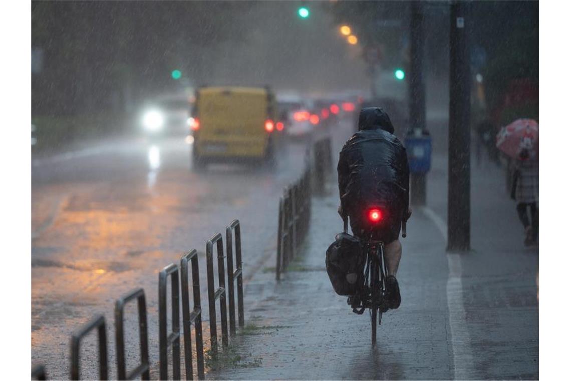 Ein Radfahrer fährt durch den strömenden Regen in Frankfurt. Bei der Feuerwehr gingen zahlreiche Notrufe ein. Foto: Sebastian Gollnow/dpa