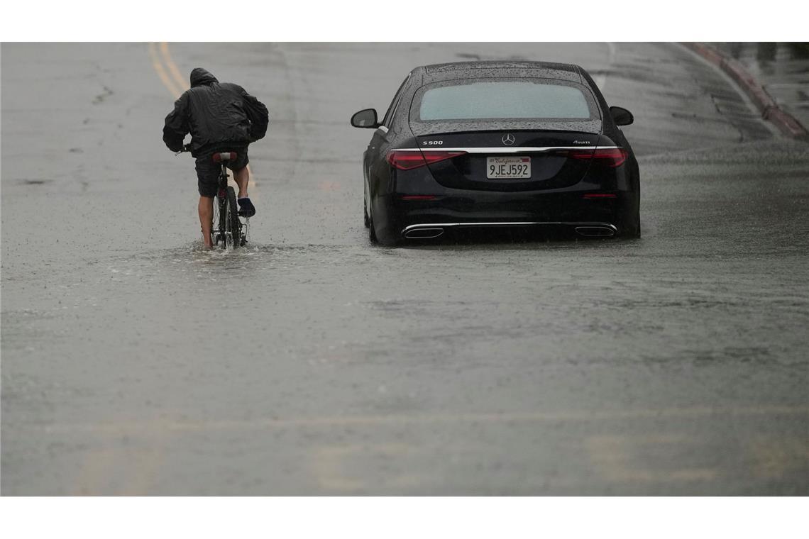 Ein Radfahrer fährt durch eine überflutete Straße.