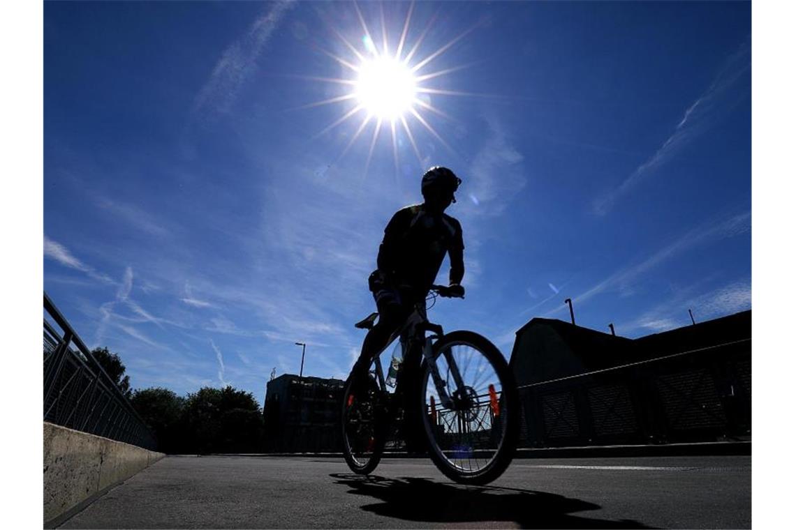 Ein Radfahrer fährt in der Sonne über einen Radweg. Foto: Oliver Berg/dpa