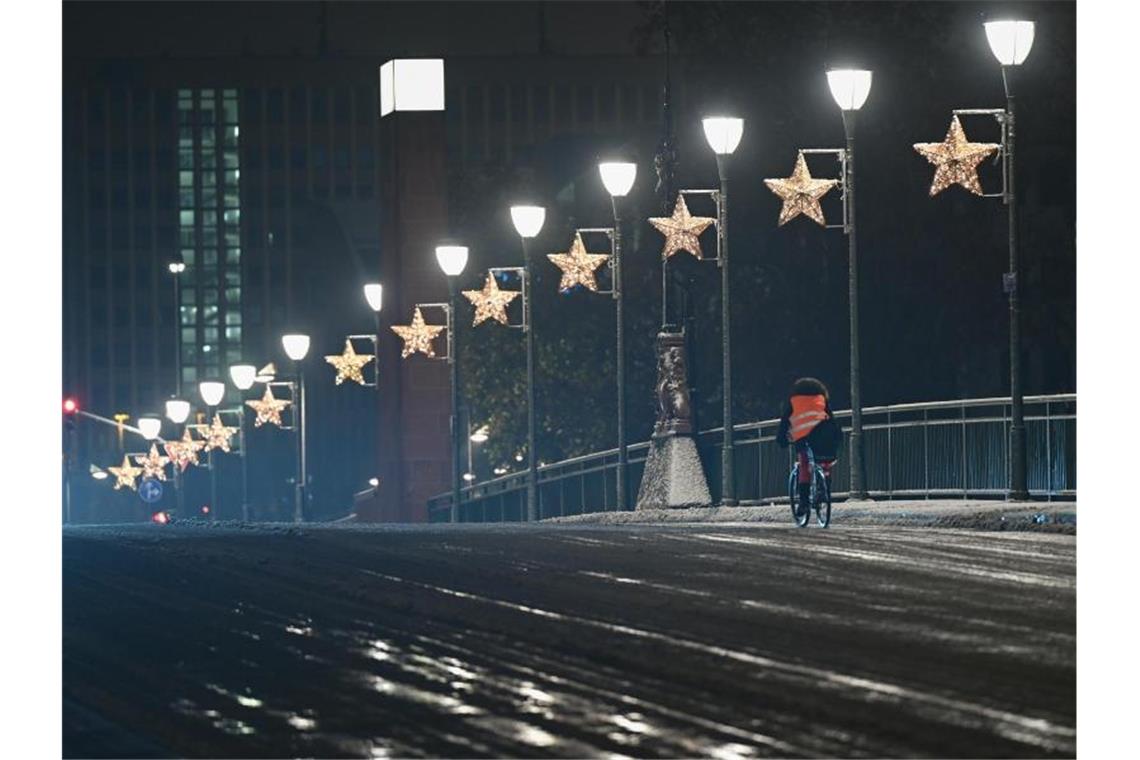 Ein Radfahrer ist nach einem Wintereinbruch in der Nacht auf der Alten Brücke in Frankfurt unterwegs. Foto: Arne Dedert/dpa