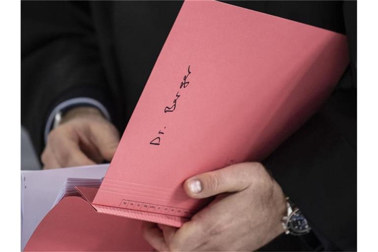 Ein Rechtsanwalt des Hauptbeschuldigten Hanno Berger mit eine Akte mit der Aufschrift „Dr. Berger“. Foto: Boris Roessler/dpa/Archiv