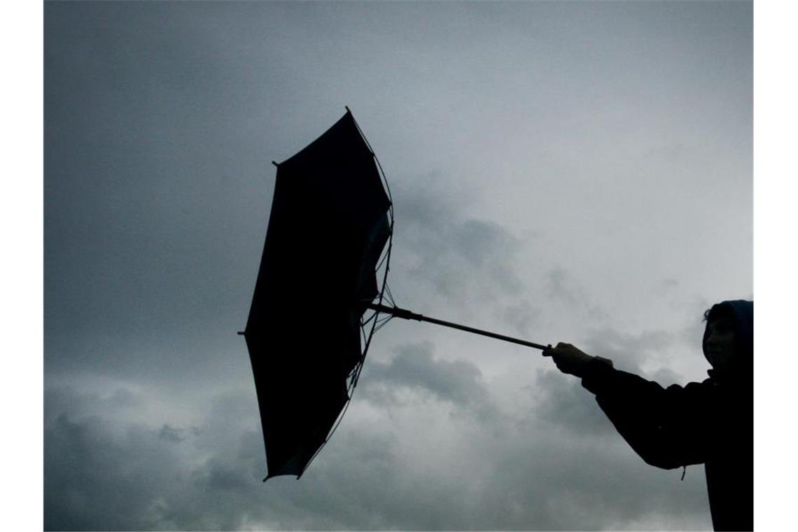 Ein Regenschirm einer Fußgängerin wird von einer Winböe erfasst. Foto: picture alliance / Karl-Josef Hildenbrand/dpa/Archivbild