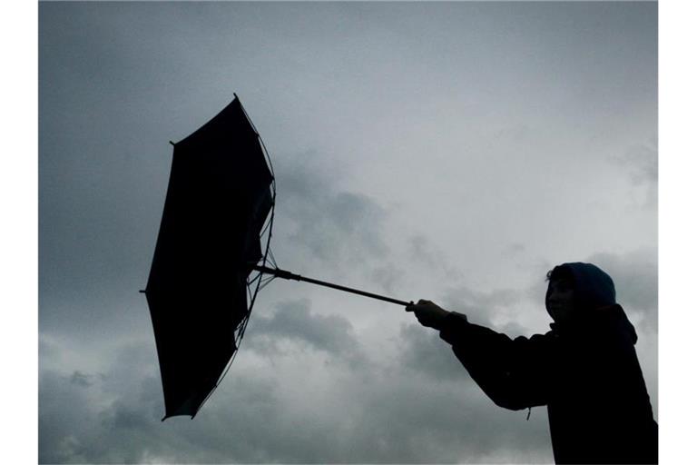Ein Regenschirm eines Spaziergängers wird von einer Windböe erfasst. Foto: picture alliance / Karl-Josef Hildenbrand/dpa/Symbolbild