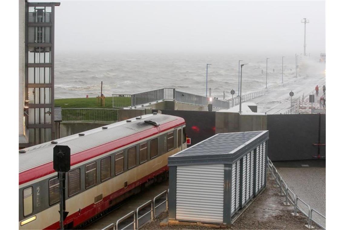 Ein Regionalzug steht bei starkem Sturm vor einem geschlossenen Tor am Fähranleger Dagebüll. Foto: Bodo Marks/dpa