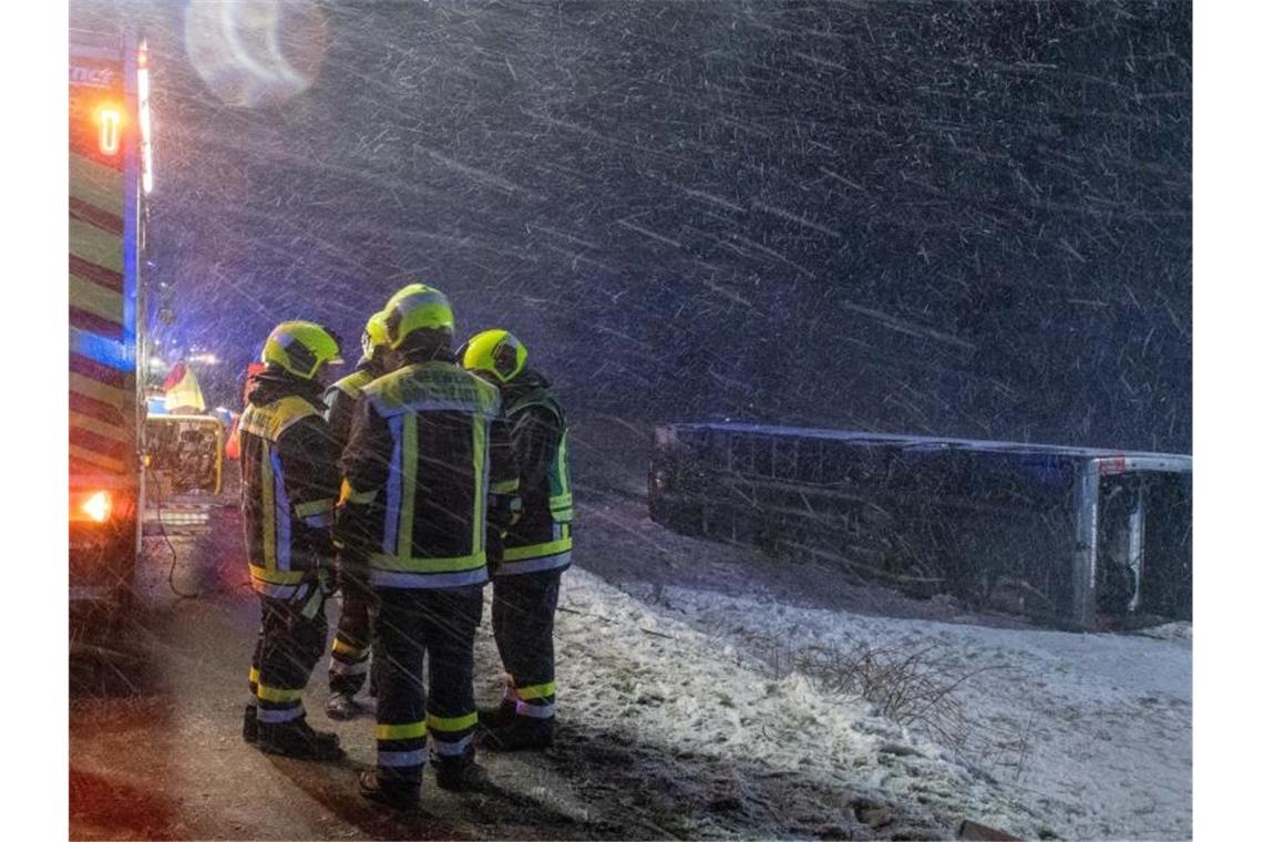 Ein Reisebus liegt umgestürzt neben der B10 bei Tomerdingen nördlich von Ulm in einem Feld. Bei schneeglatter Fahrbahn und starkem Wind kam der Bus von der Straße ab. Foto: Stefan Puchner/dpa
