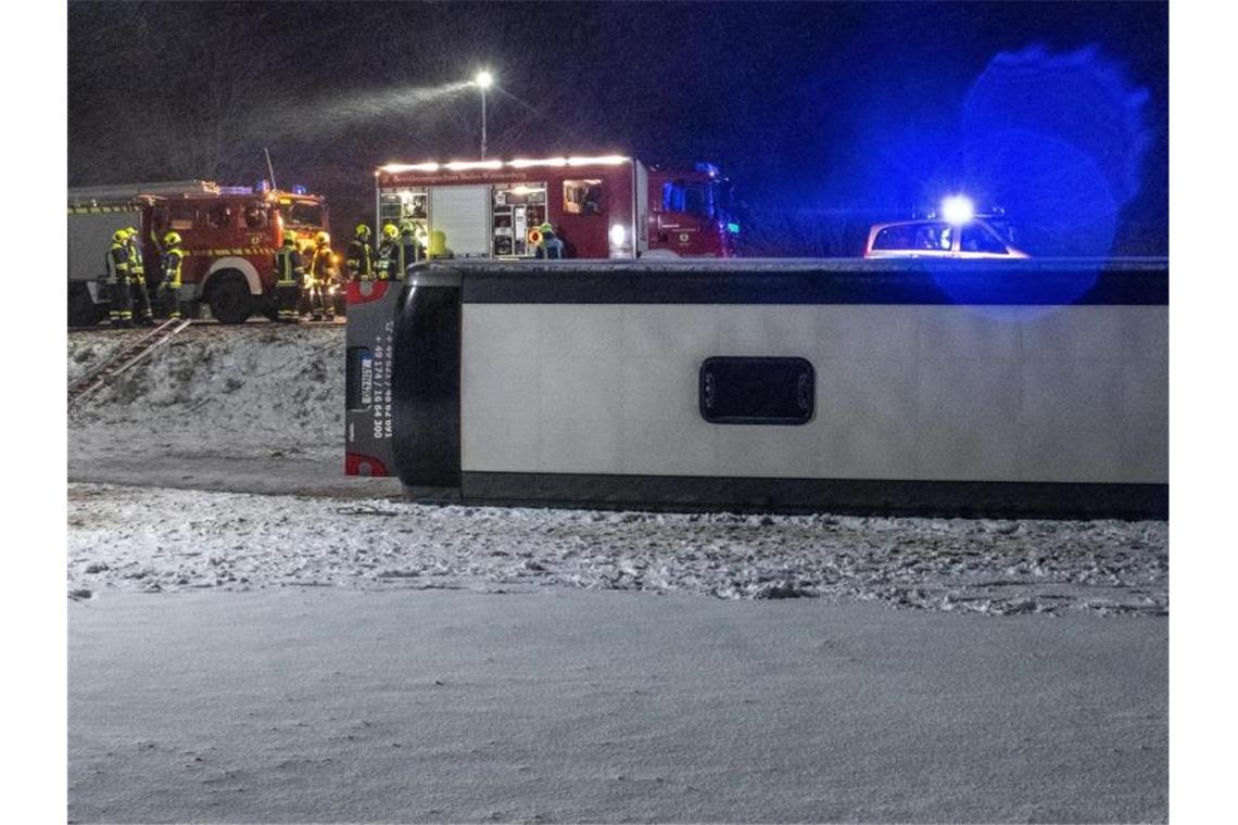 Ein Reisebus liegt umgestürzt neben der B10 bei Tomerdingen nördlich von Ulm in einem Feld. Bei schneeglatter Fahrbahn und starkem Wind kam der Bus von der Straße ab. Foto: Stefan Puchner/dpa