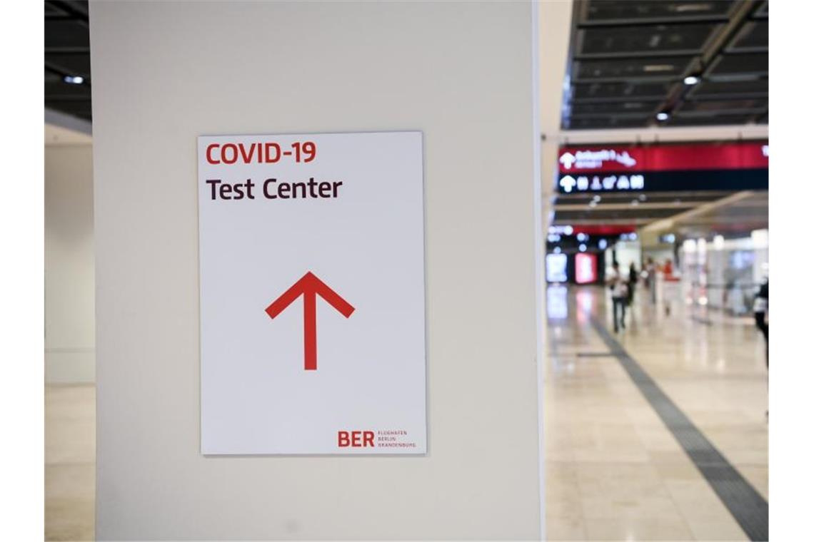 Coronavirus-Reproduktionszahl steigt über Schwelle von 1 Ein Reisender geht im Flughafen Berlin-Brandenburg (BER) mit einem Koffer nahe eines Hinweisschildes mit der Aufschrift „Covid-19 Test Center“. Foto: Jens Kalaene/dpa-Zentralbild/dpa