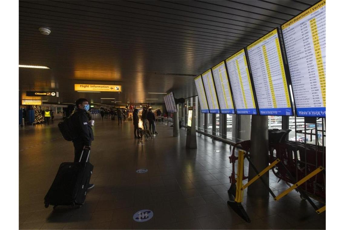 Ein Reisender schaut auf die Anzeigetafeln mit den Abflügen am Flughafen Schiphol bei Amsterdam. Foto: Peter Dejong/AP/dpa/Archivbild